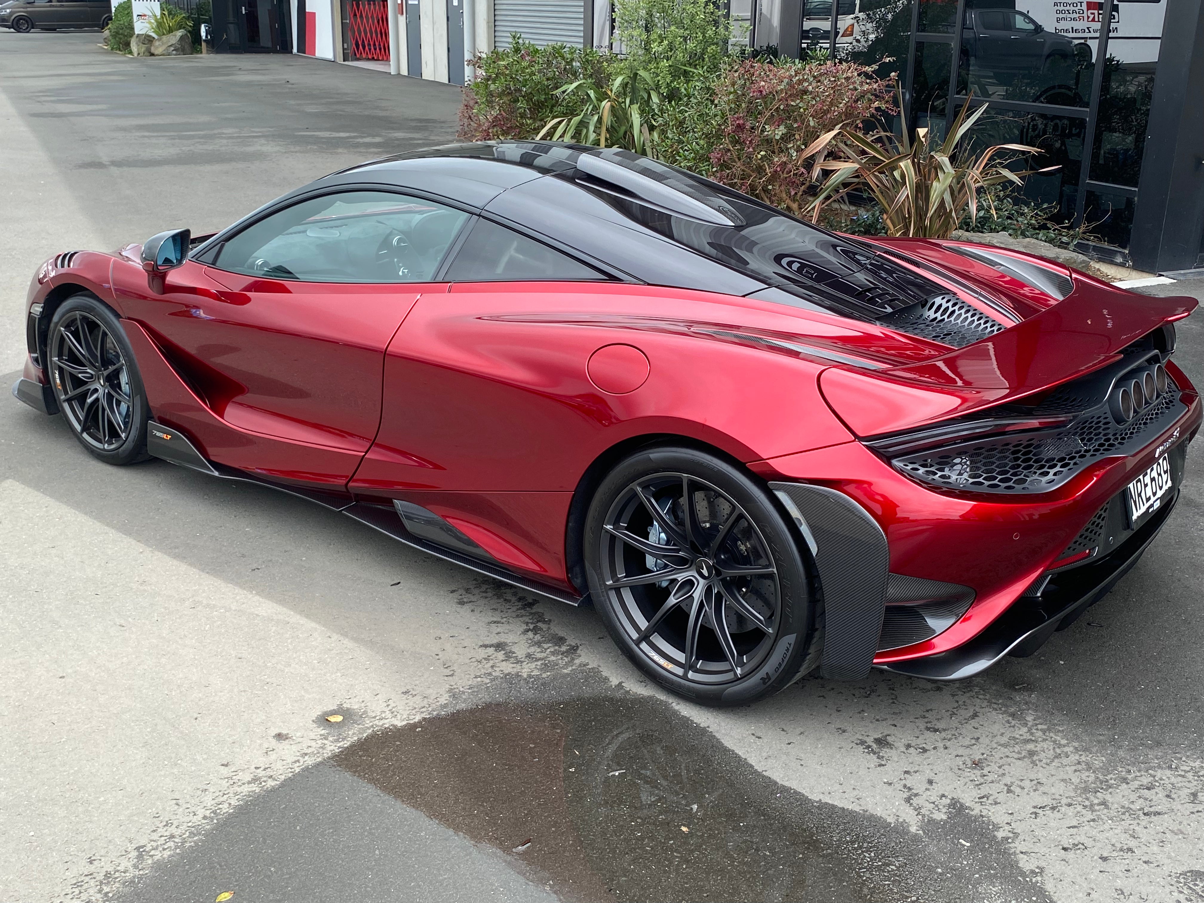Rear 3/4 view of 2021 McLaren 765LT For Sale by Prime Speed Sport in New Zealand. Highly specced with full carbon pack and finished in MSO optioned Volcano Red exterior paint.