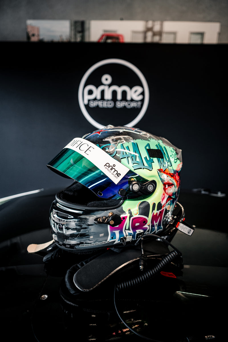 Colorful racing helmet with various stickers on a black Super Trofeo Lamborghini, in a Prime Speed Sport Garage. 