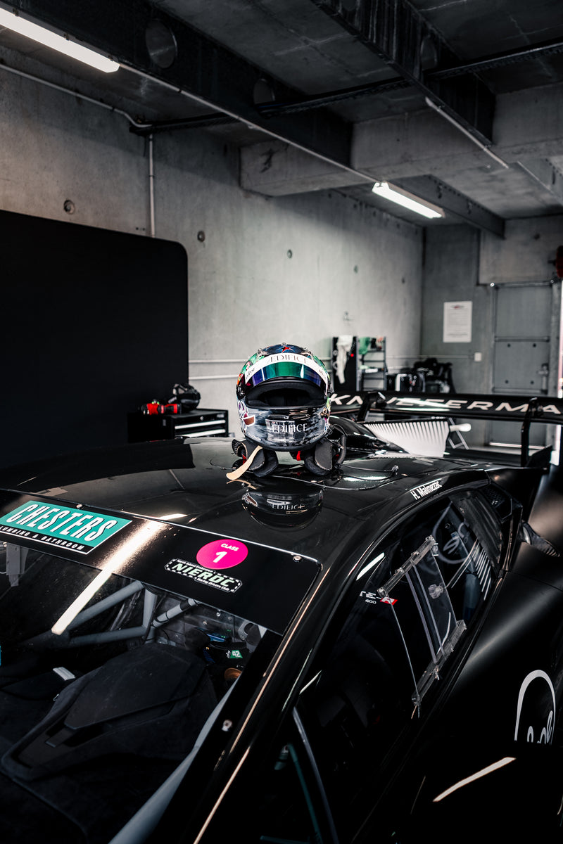 Black Super Trofeo Lamborghini with a NIERDC Series sticker on it. Mana Malmezac's Racing Helmet sitting on top of the car that is covered in Aedifice branding and colours. 