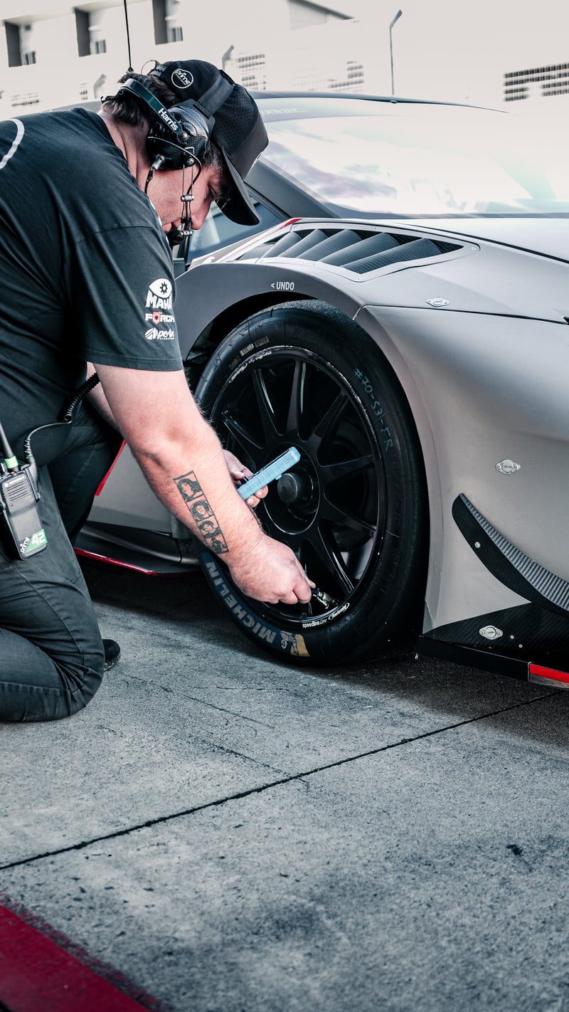 Prime Speed Sport Mechanic Sam Robinson checking the tyre pressure on a Lamborghini Super Trofeo before it goes out to track at Hampton Downs International Motorsport Park
