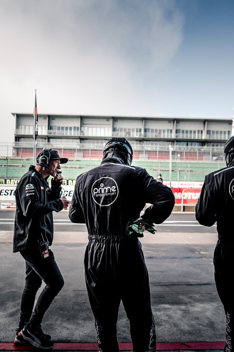 3 Prime Speed Sport Race Mechanics at Hampton Downs International Motorsport Park. Two in race suits and one talking on the race radios. 