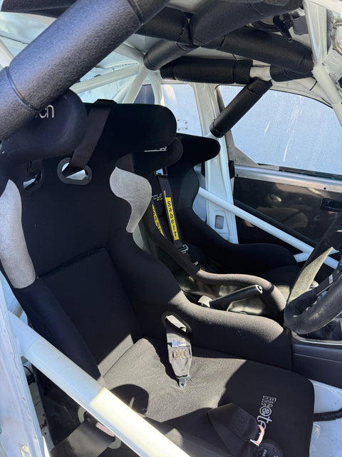Close-up of a Subaru Impreza vehicle's interior with black seats, seatbelts and steering wheel.